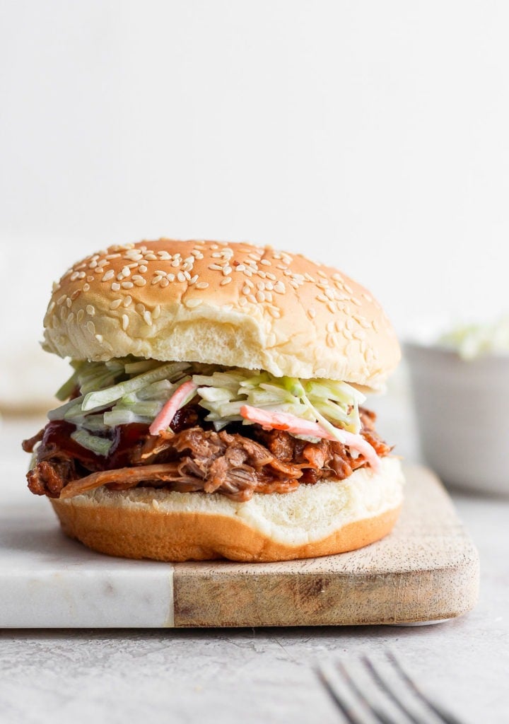 pulled pork in bun on cutting board