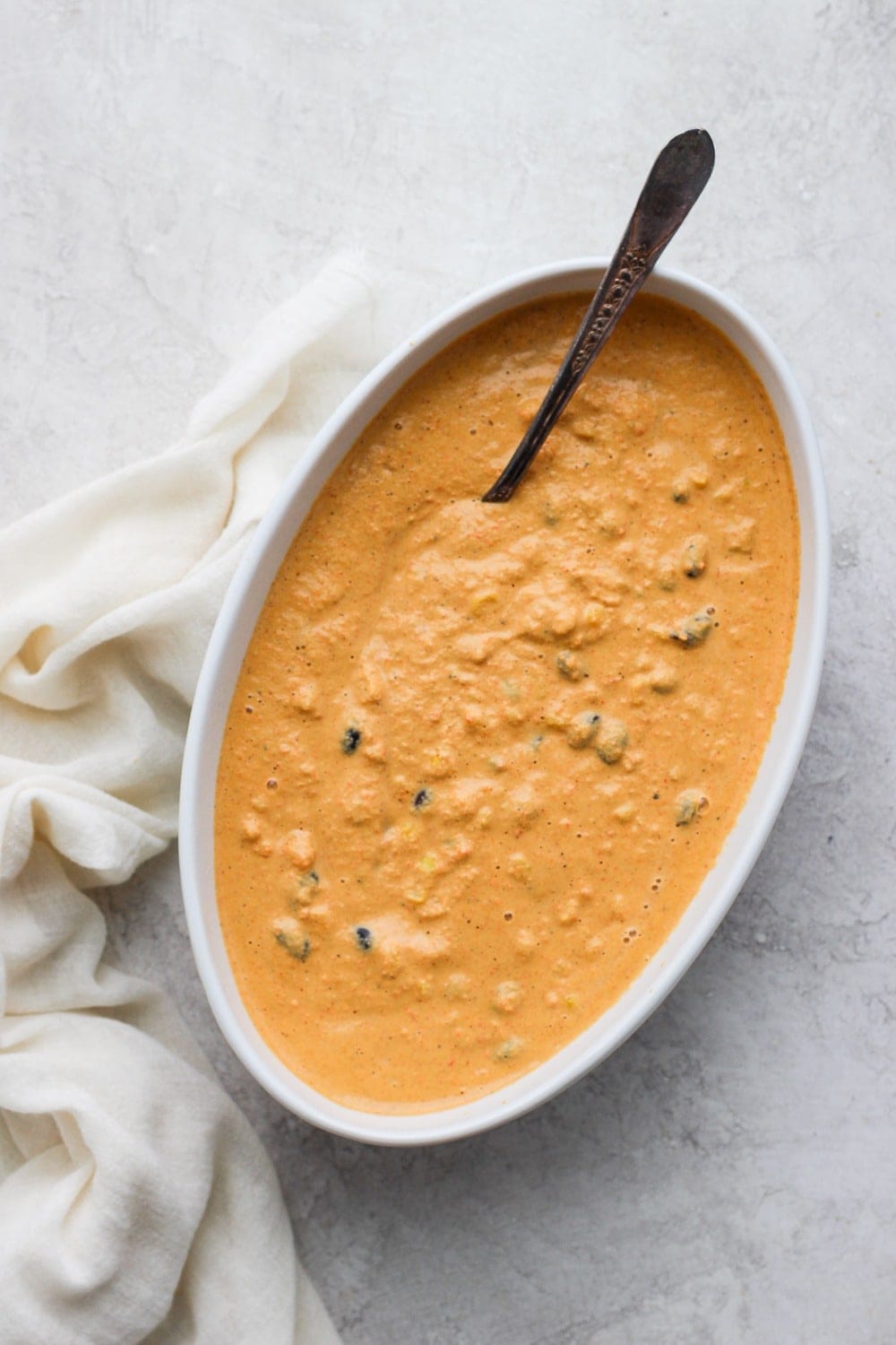 vegan street corn queso dip in a serving bowl with a spoon