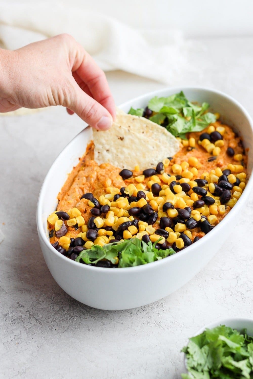 vegan street corn queso dip with a tortilla chip being dipped in it