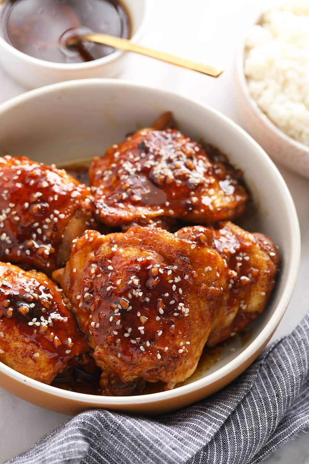 Chicken thighs in a bowl with sesame seeds on top. 