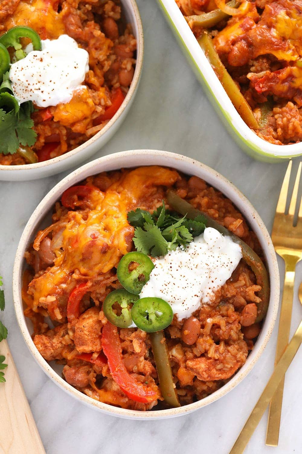 chicken burrito bowl casserole in a bowl topped with sliced jalapeños and a dollop of greek yogurt