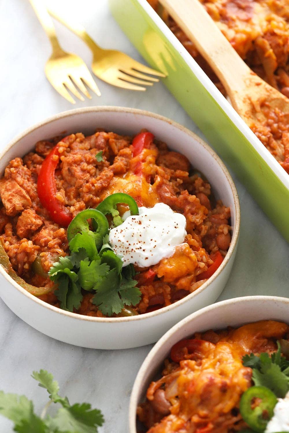 healthy chicken burrito bowl casserole in a bowl topped with sliced jalapenos and a dollop of greek yogurt