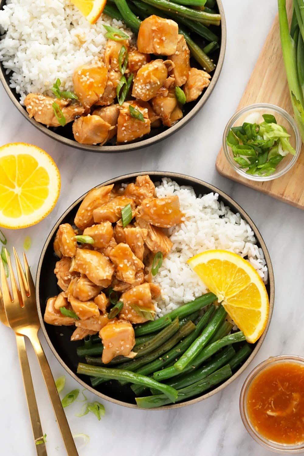 orange chicken on a plate with rice and beans