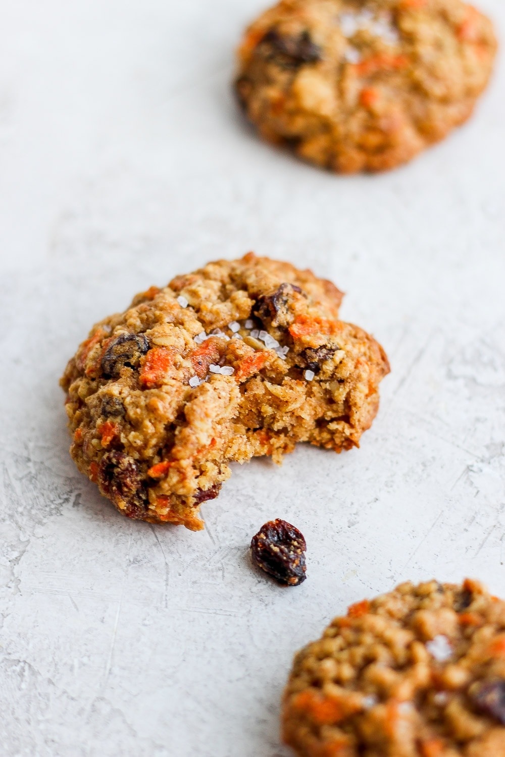 A carrot cake cookie with a bite taken out of it. 