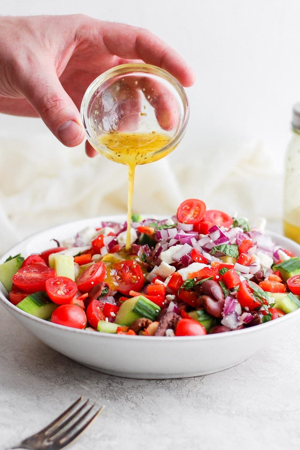 Pouring dressing onto the Greek Salad