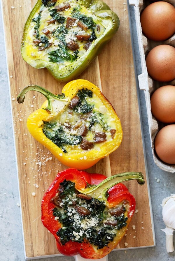 Cheesy breakfast stuffed pepper with eggs and spinach on a cutting board.
