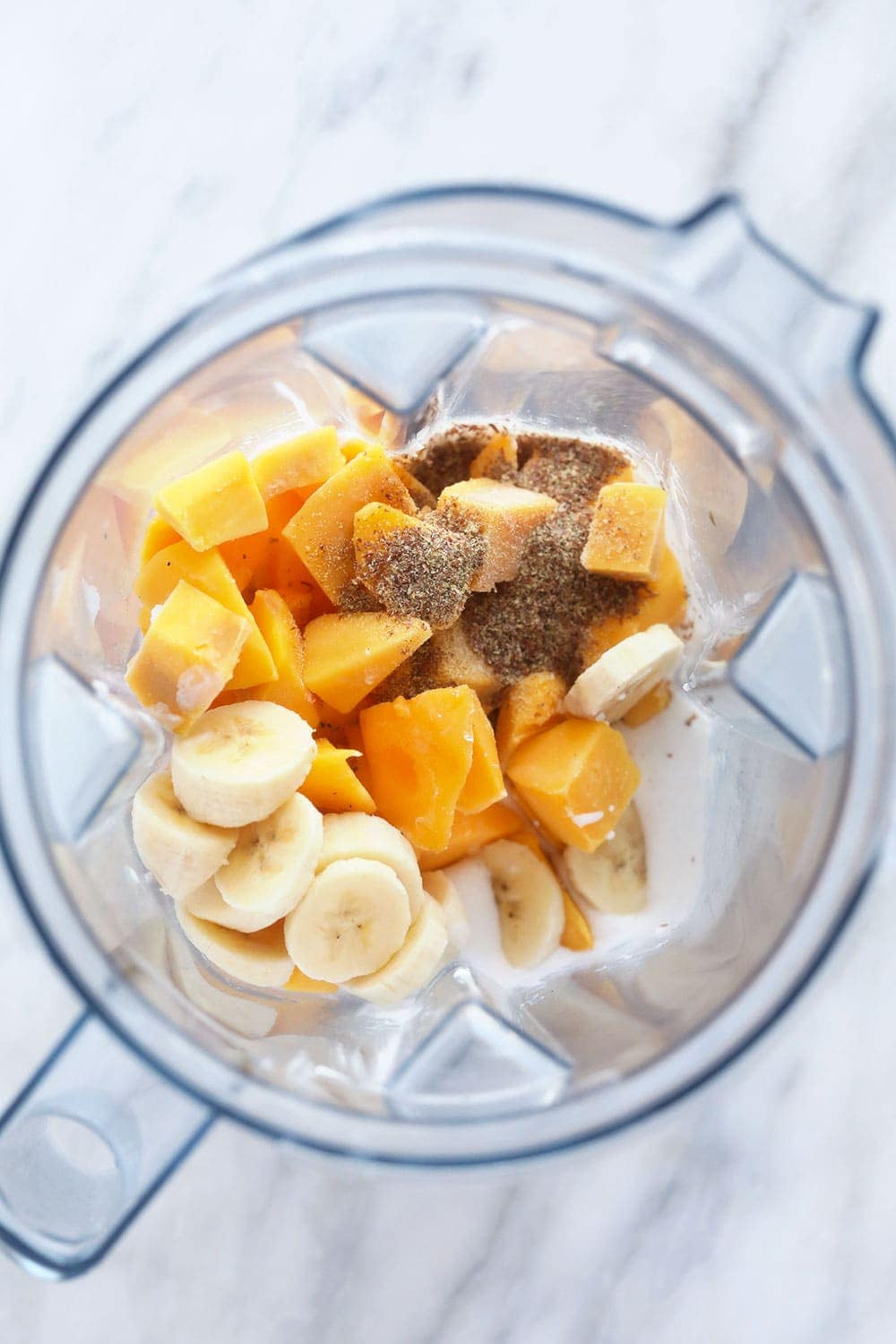 mango smoothie ingredients in a blender ready to be made into a smoothie