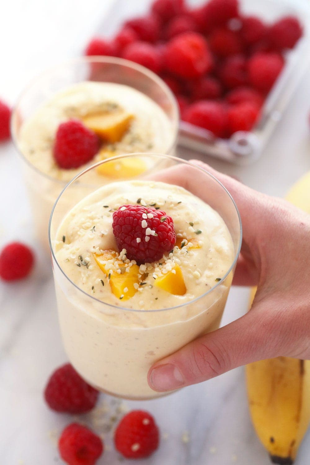 mango smoothie topped with a raspberry and sliced mango 