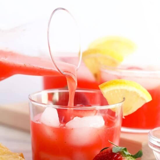 A glass of strawberry lemonade infused with a splash of strawberry vodka being poured into a glass.