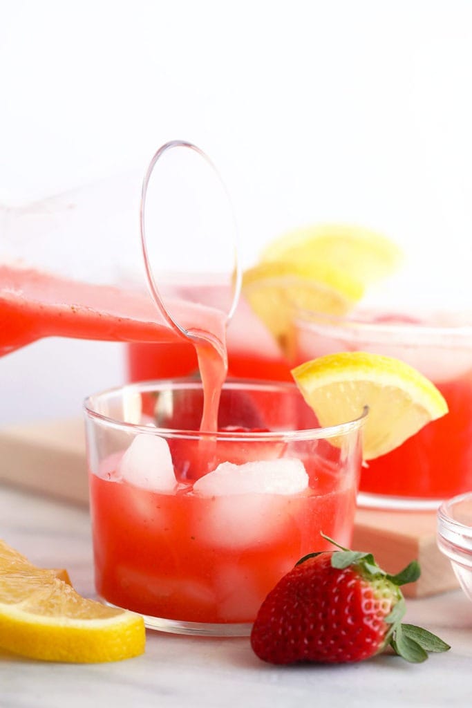 a glass of spiked strawberry lemonade being poured.