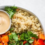A coconut quinoa bowl with carrots and a dipping sauce.