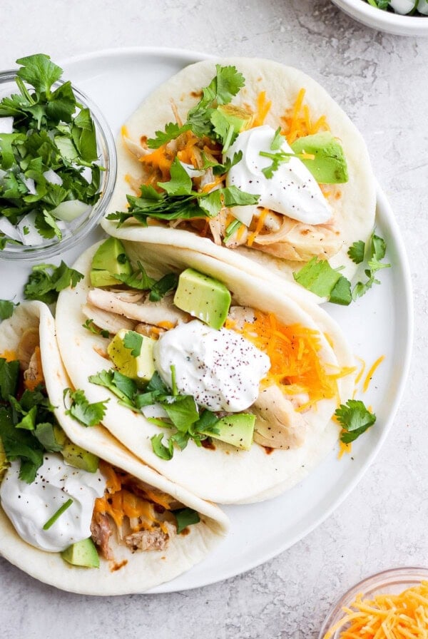shredded chicken tacos topped with avocado and a dollop of greek yogurt