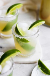 Skinny margaritas garnished with lime wedges on a white plate.