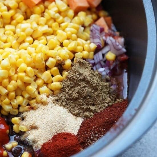 A slow cooker filled with ingredients for Mexican quinoa before cooking.