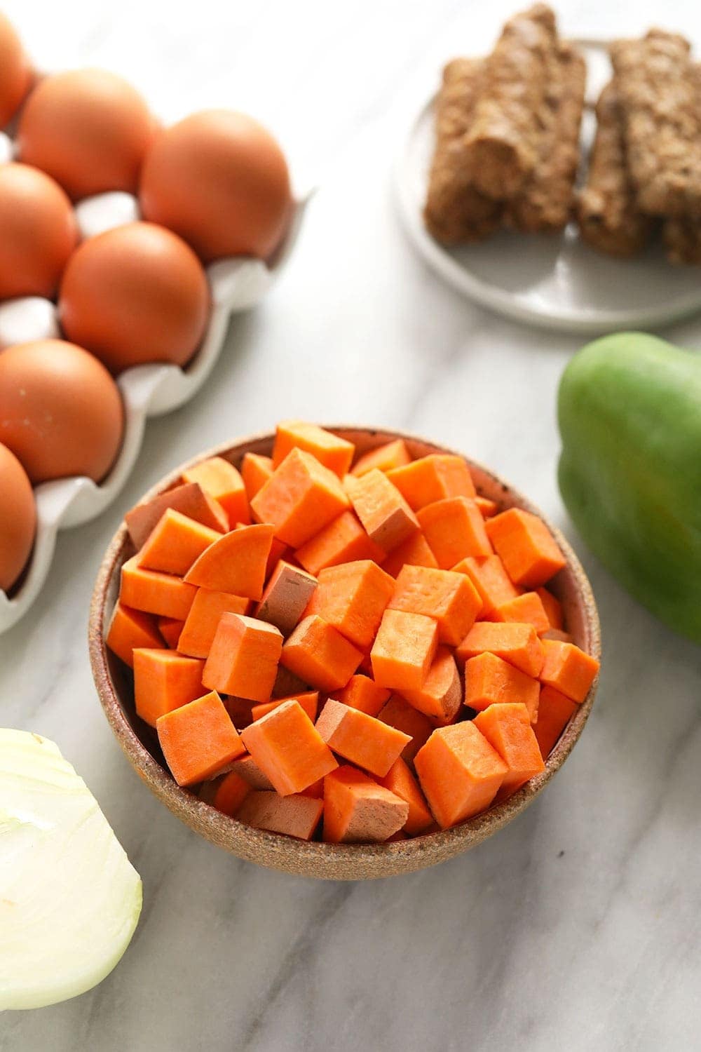 raw sweet potato, eggs, breakfast sausage, a pepper, and onion.