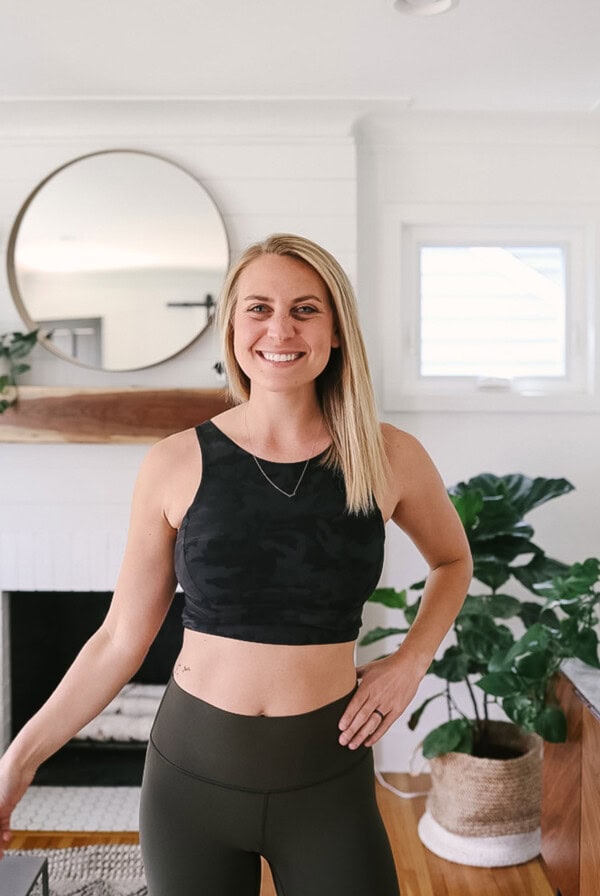 a woman in a lululemon crop top and leggings standing in front of a living room.
