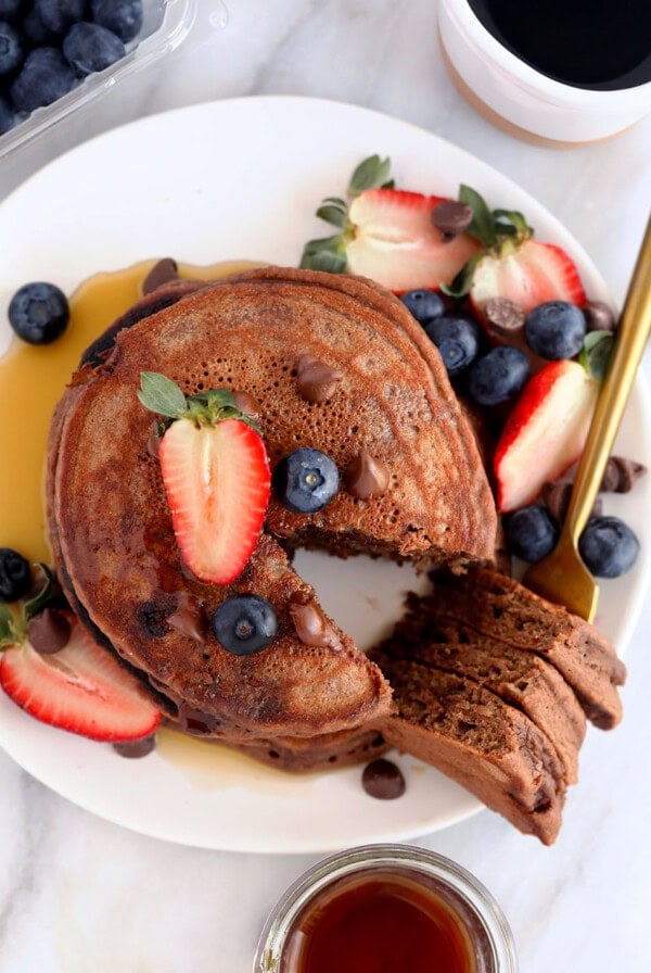 chocolate chocolate chip pancakes on a plate topped with blueberries and strawberries