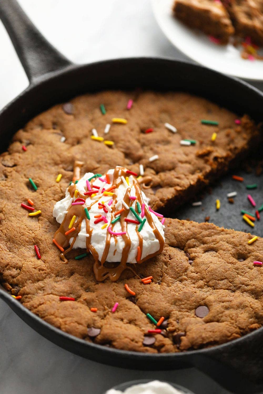 skillet cookie in cast iron pan with whipped cream and sprinkles