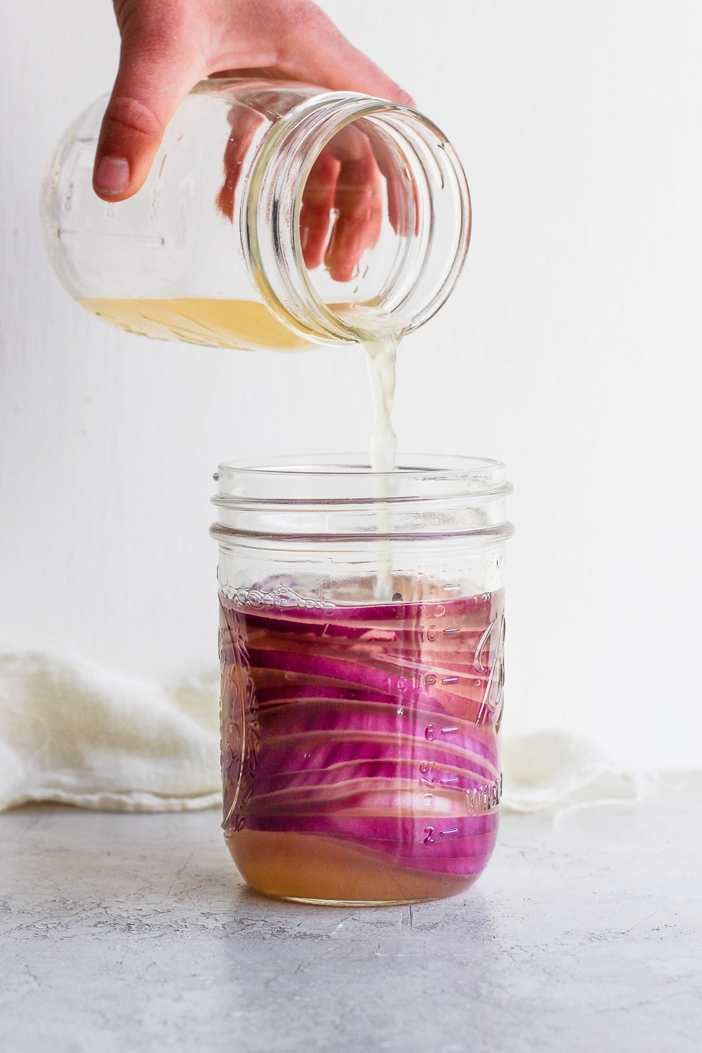 Pouring Vinegar into the mason jar with onions