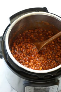 Instant Pot baked beans cooked with a wooden spoon.