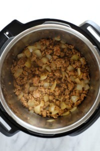 an Instant Pot filled with meat, onions, and baked beans.