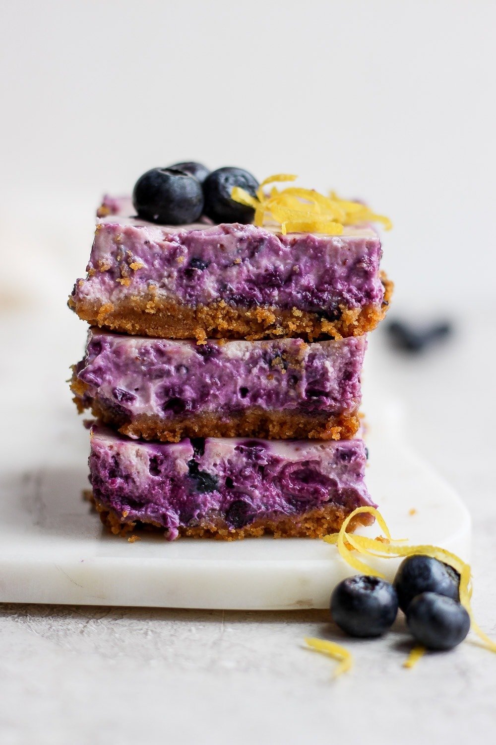 blueberry cheesecake bars stacked three high looking delicious and ready to eat.
