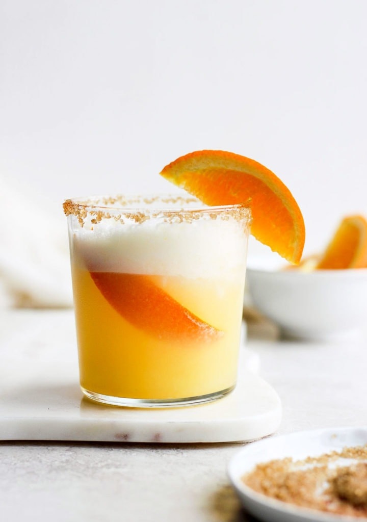 An orange cocktail garnished with a slice of orange.