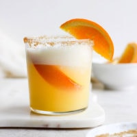 An orange cocktail garnished with a slice of orange.