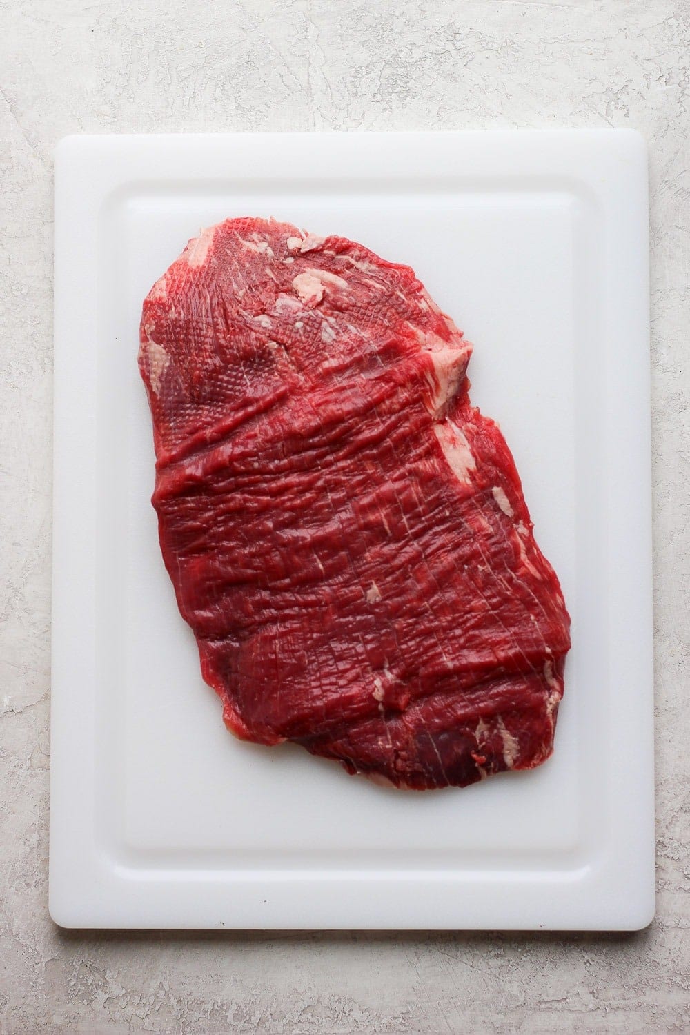 Pounded flank steak on a cutting board. 