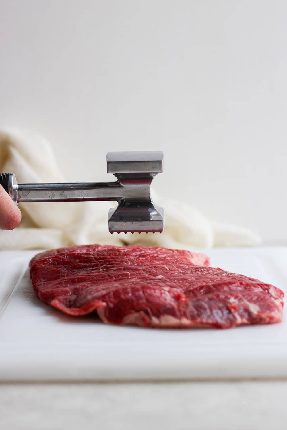 Meat tenderizer pounding flank steak.