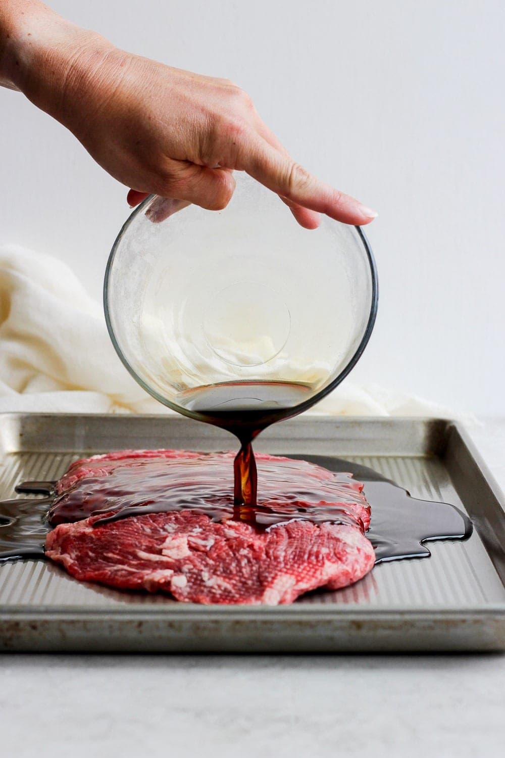 Pouring marinade over flank steak. 