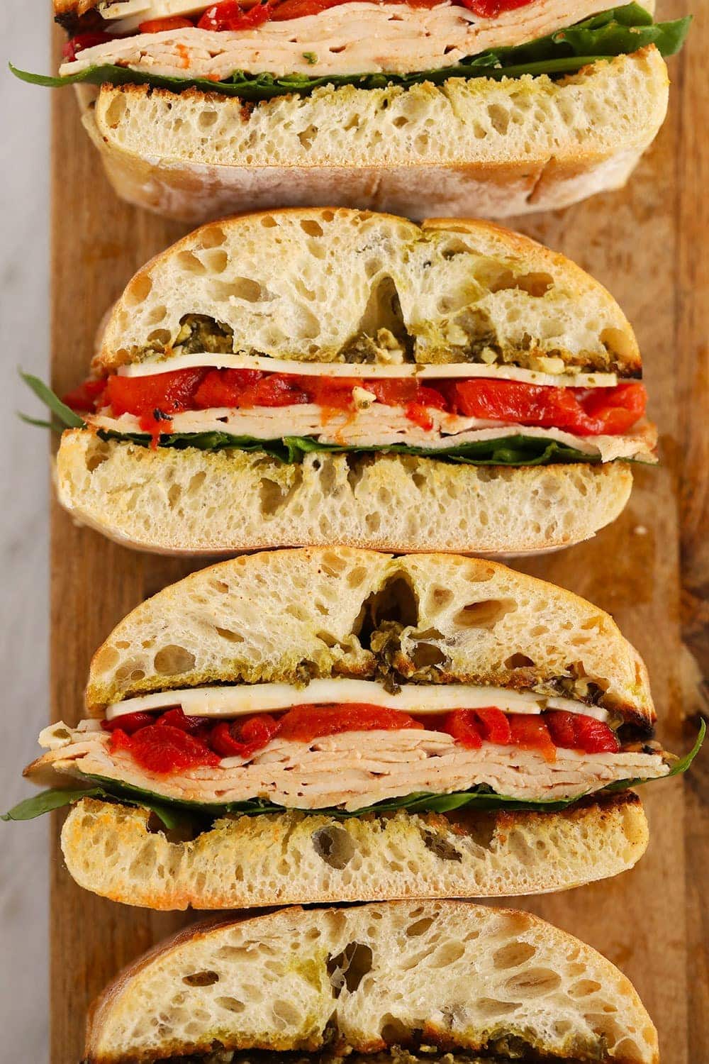 Grilled Roasted Red Pepper, Pesto & Turkey Sandwich on a cutting board 