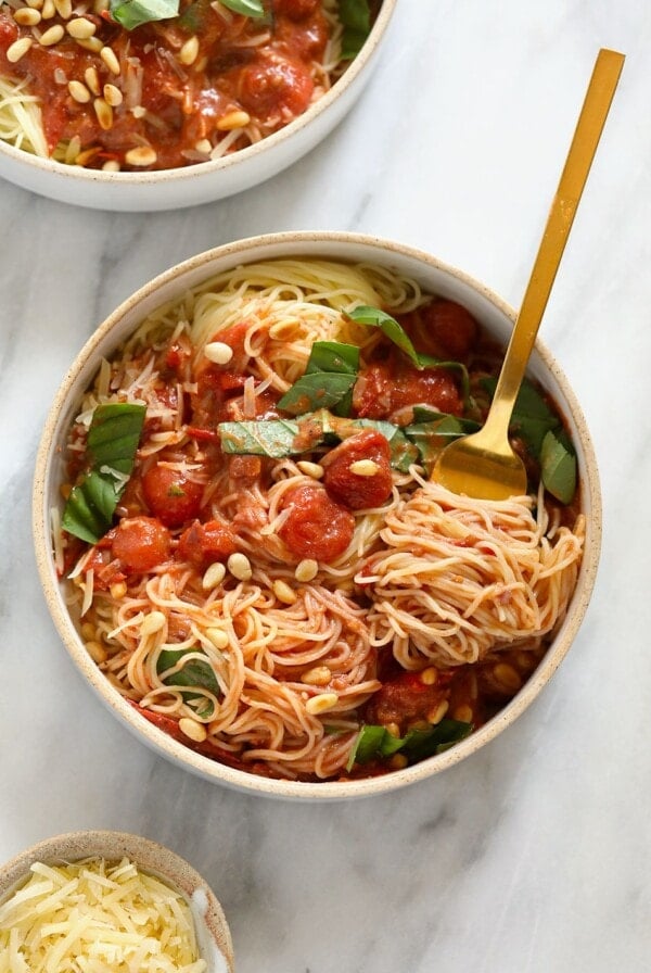 Two bowls of summer pasta with tomato sauce and pine nuts.