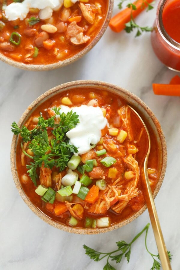 Two bowls of buffalo chicken chili soup with sour cream and carrots.
