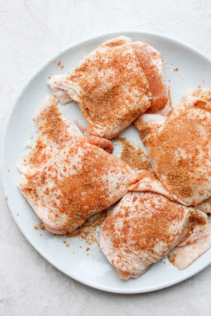 chicken thighs on plate with dry rub.