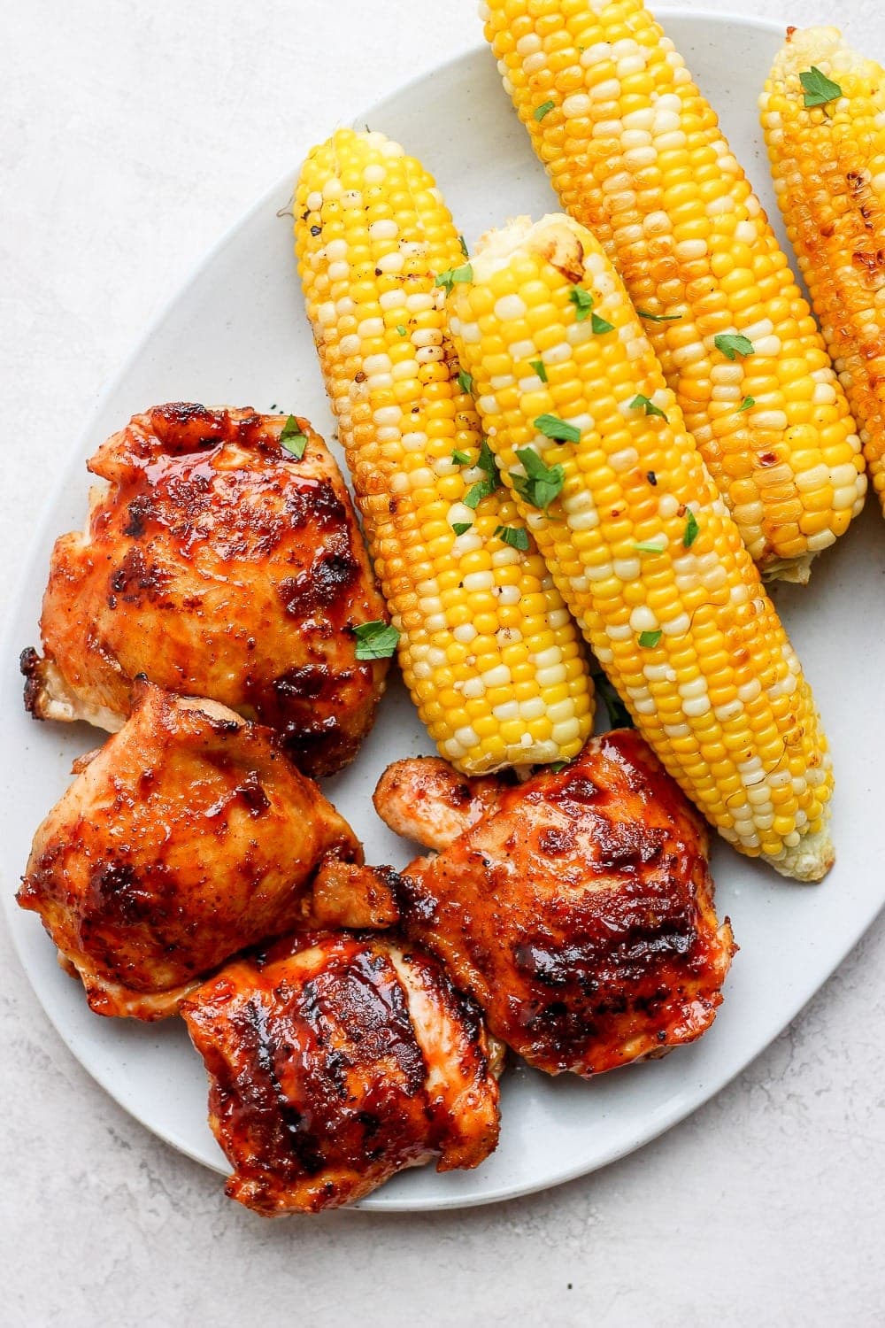grilled chicken thighs with corn on plate.