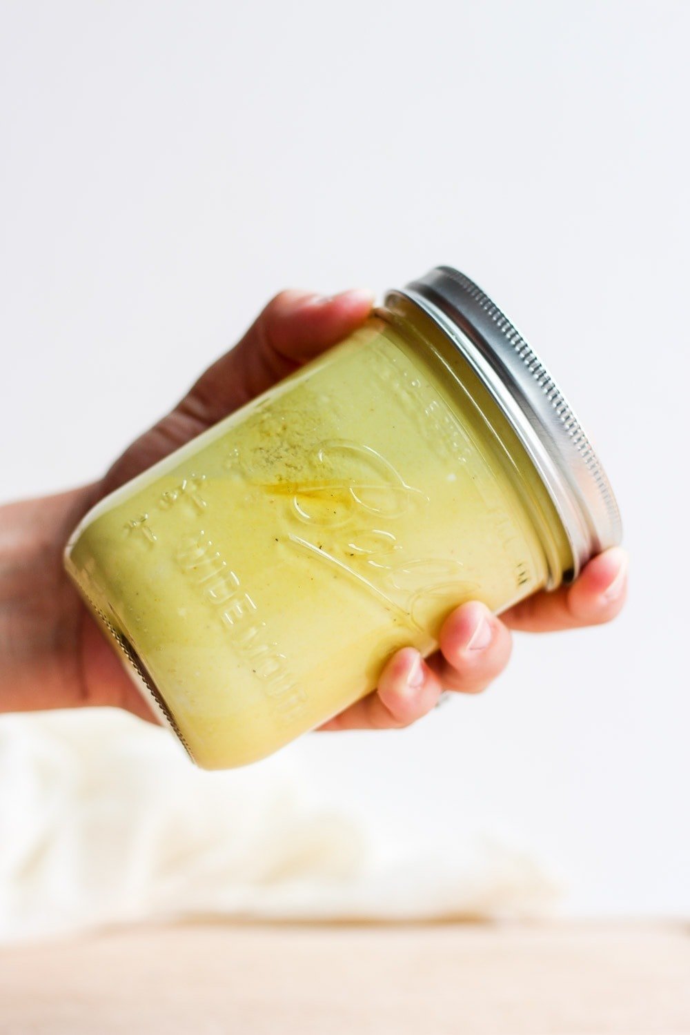 hand shaking honey mustard dressing in jar