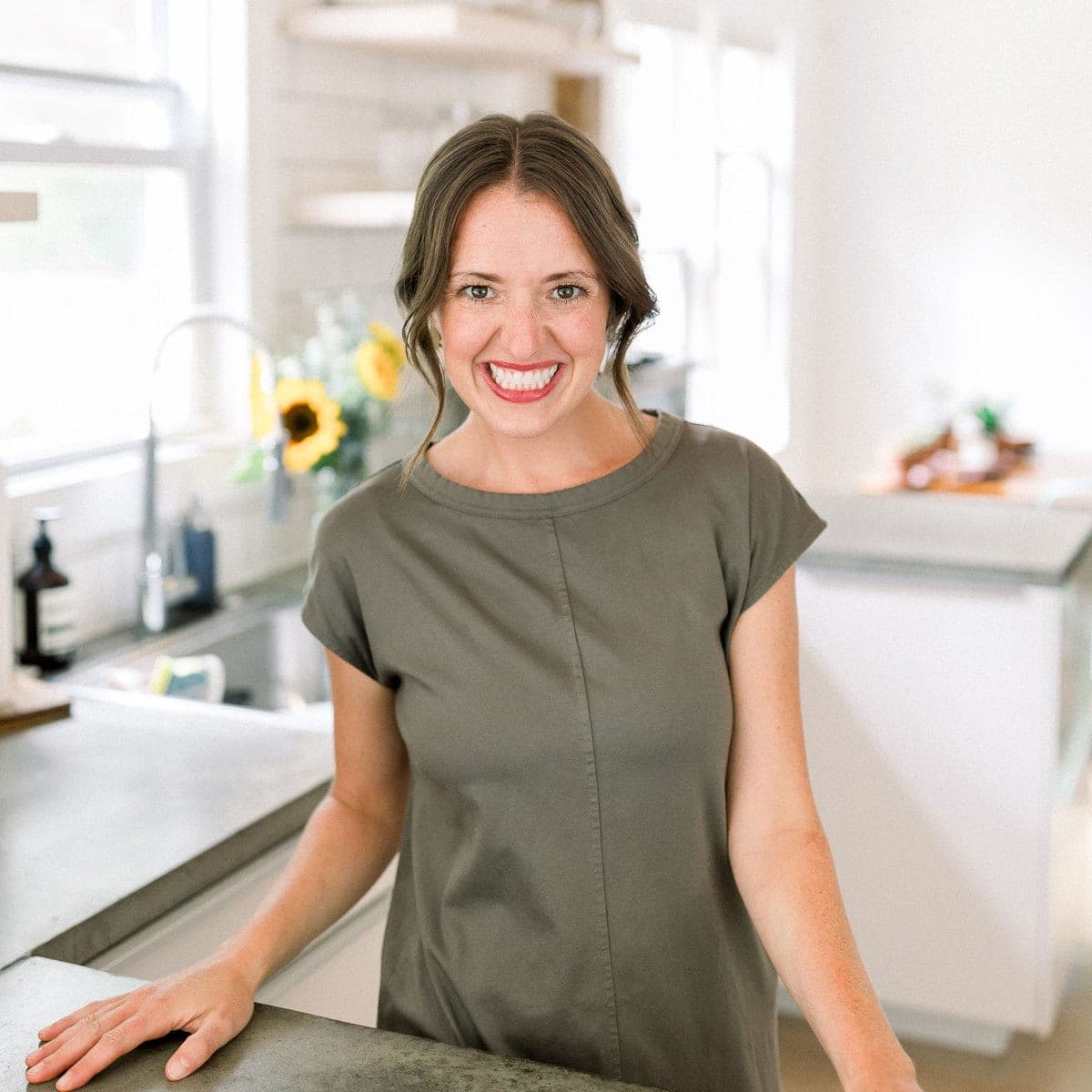 A fit foodie finds woman standing in front of a kitchen counter wearing a gray shirt.