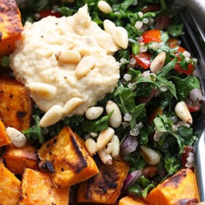 A bowl of sweet potato and kale salad with hummus.