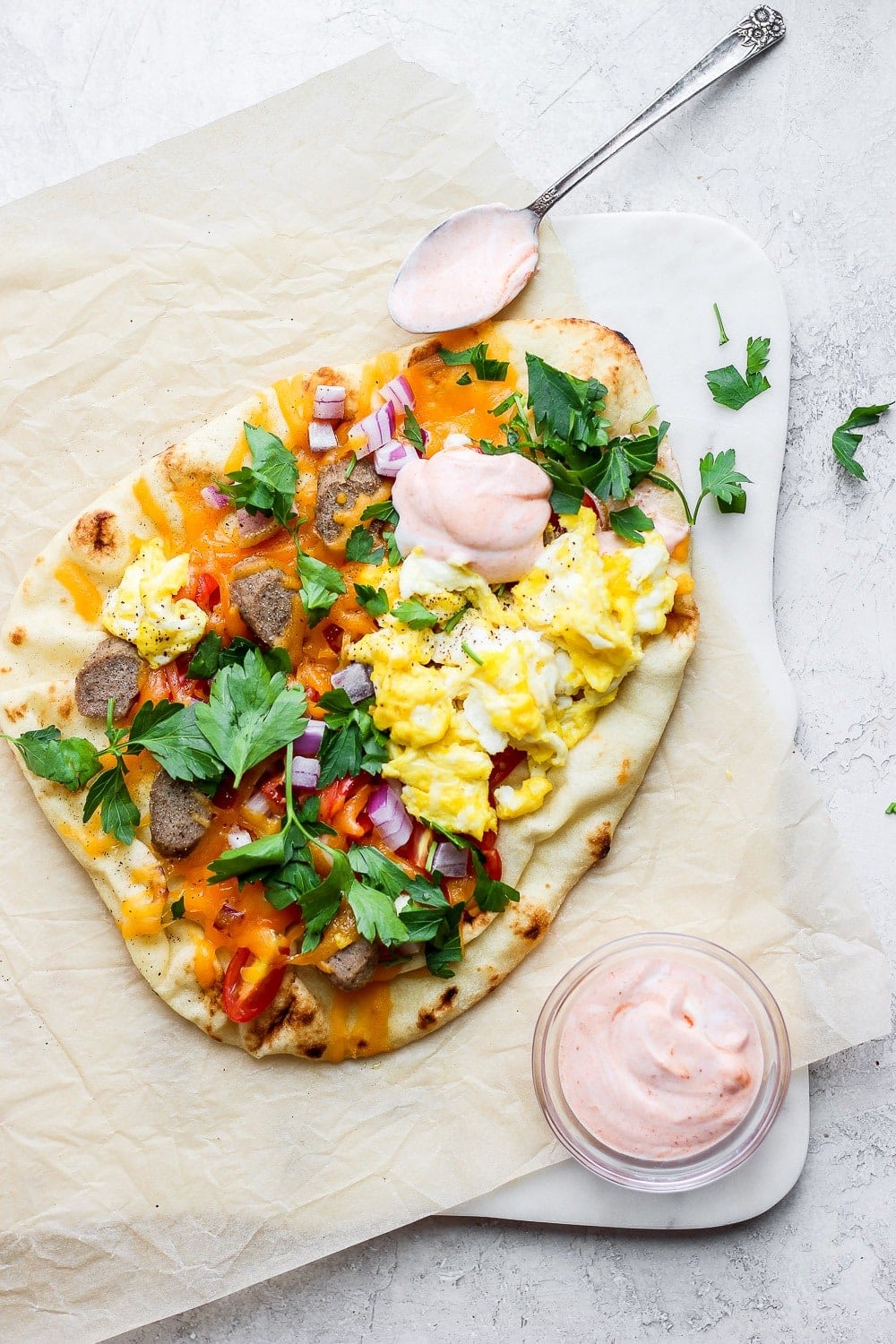 Naan pizza topped with chicken sausage, eggs, tomatoes, and red onion. 
