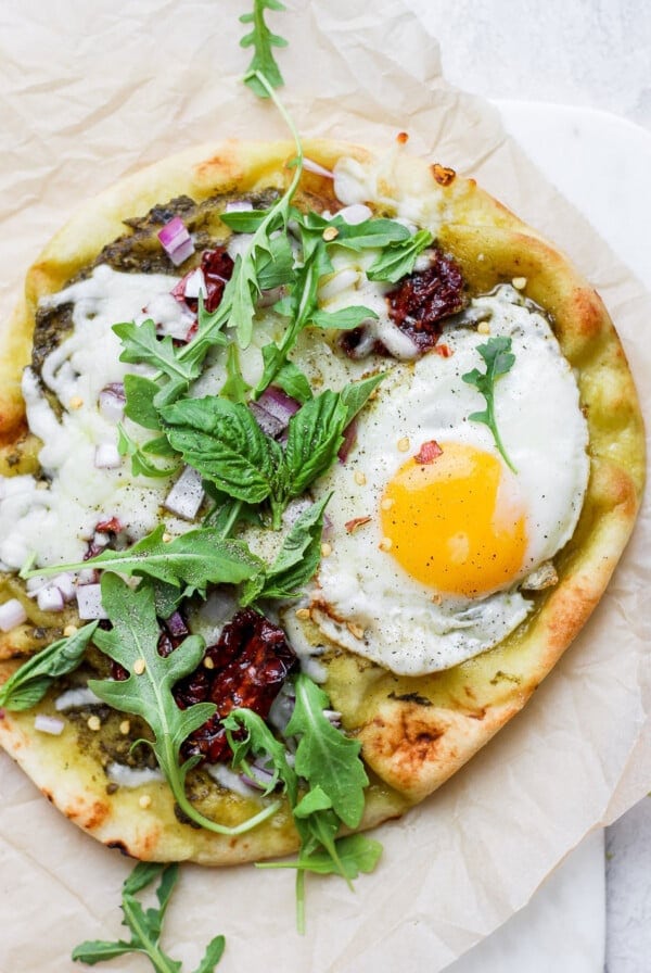 A Naan pizza topped with egg and greens.