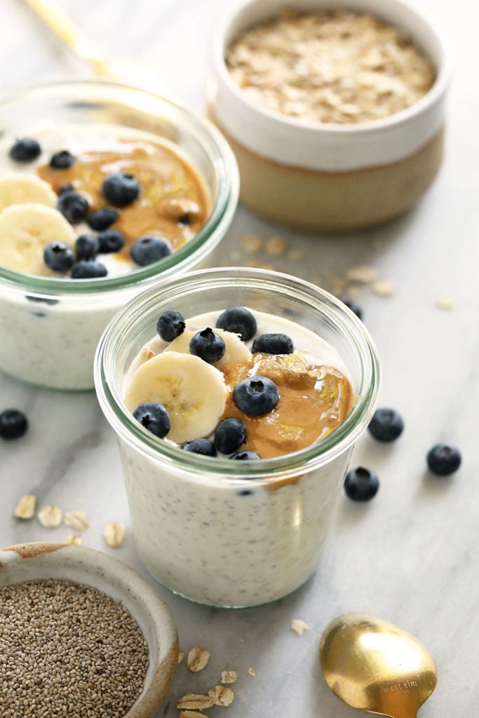 Overnight Oats im Glas mit 2 Schalen Haferflocken.