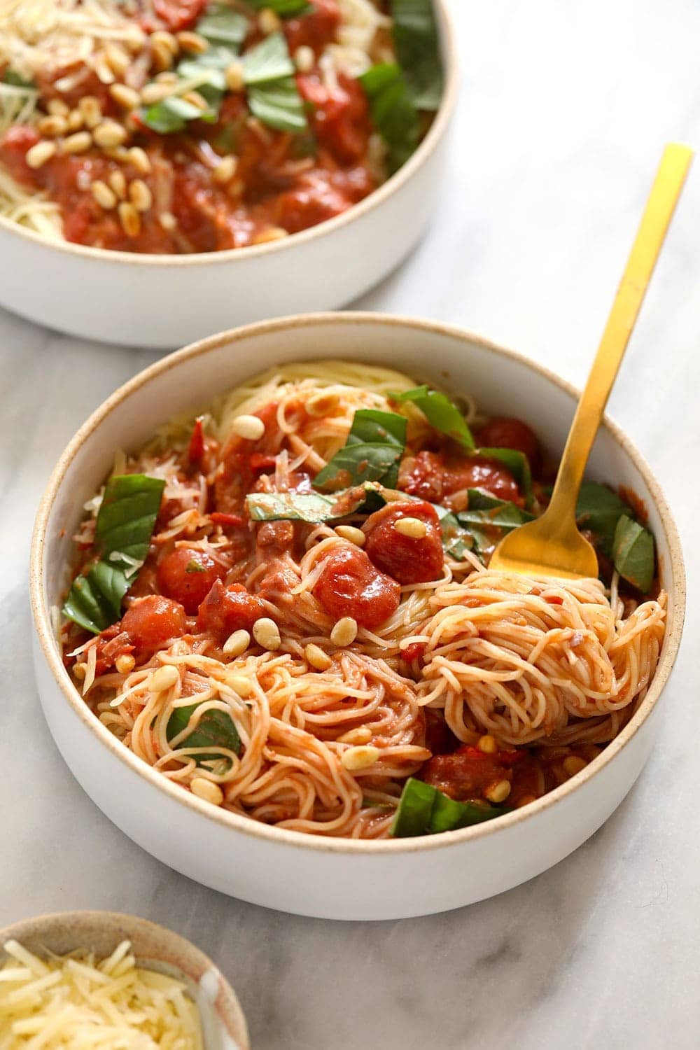 Two bowls of garden summer pasta with fresh basil on top. 