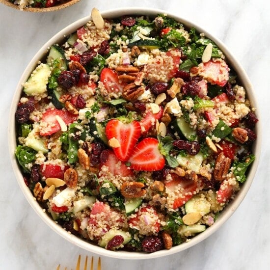 a bowl of quinoa salad with strawberries and nuts.
