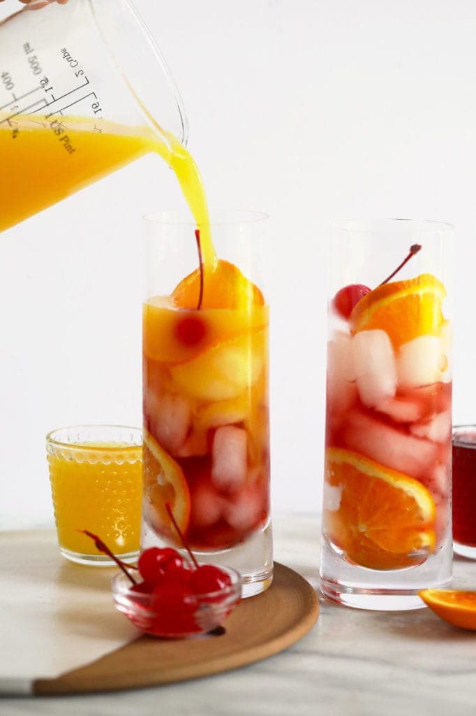 Pouring orange juice into a sex on the beach cocktail. 