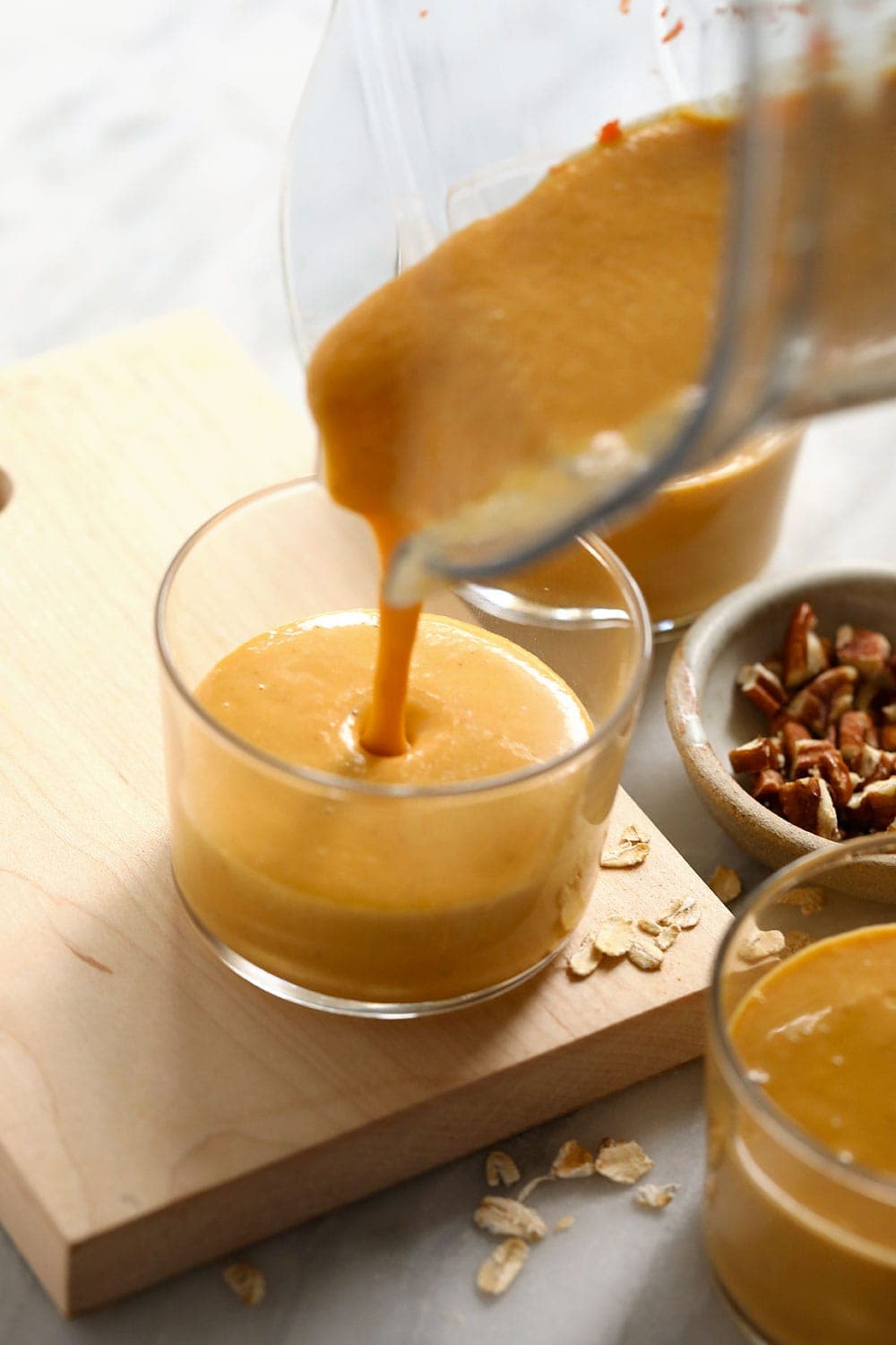 Pouring carrot cake smoothie into a glass. 