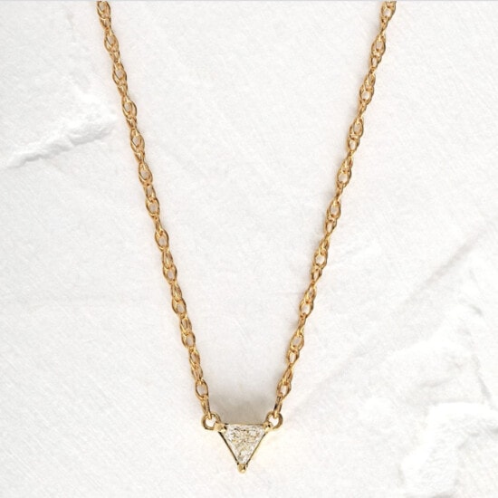 a gold triangle necklace with diamonds on it.