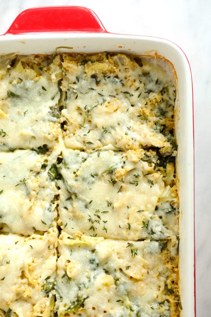 Baked spinach artichoke quinoa casserole with cheese on top. 