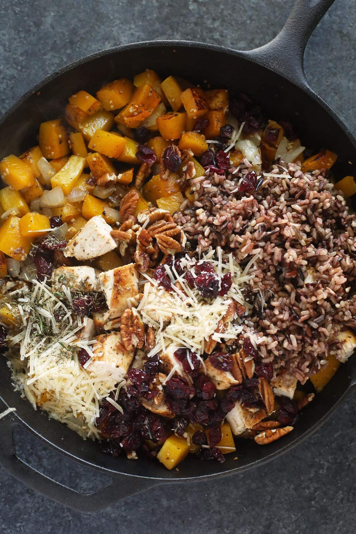 butternut squash wild rice casserole in a cast iron pan ready to be mixed together and baked