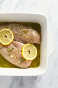 Lemon-marinated chicken breasts showcased in a white dish.